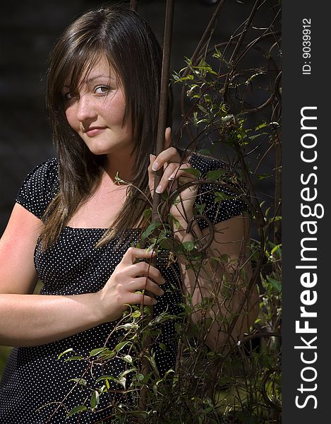 A teen girl leans against a garden arch. A teen girl leans against a garden arch.