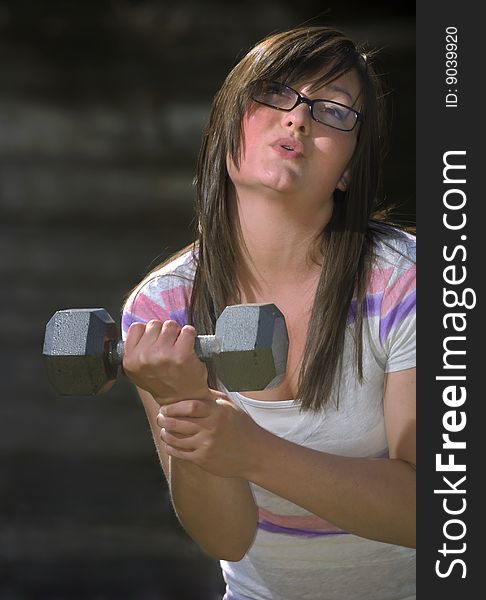 A teenager makes a funny face while curling a dumbell. A teenager makes a funny face while curling a dumbell.