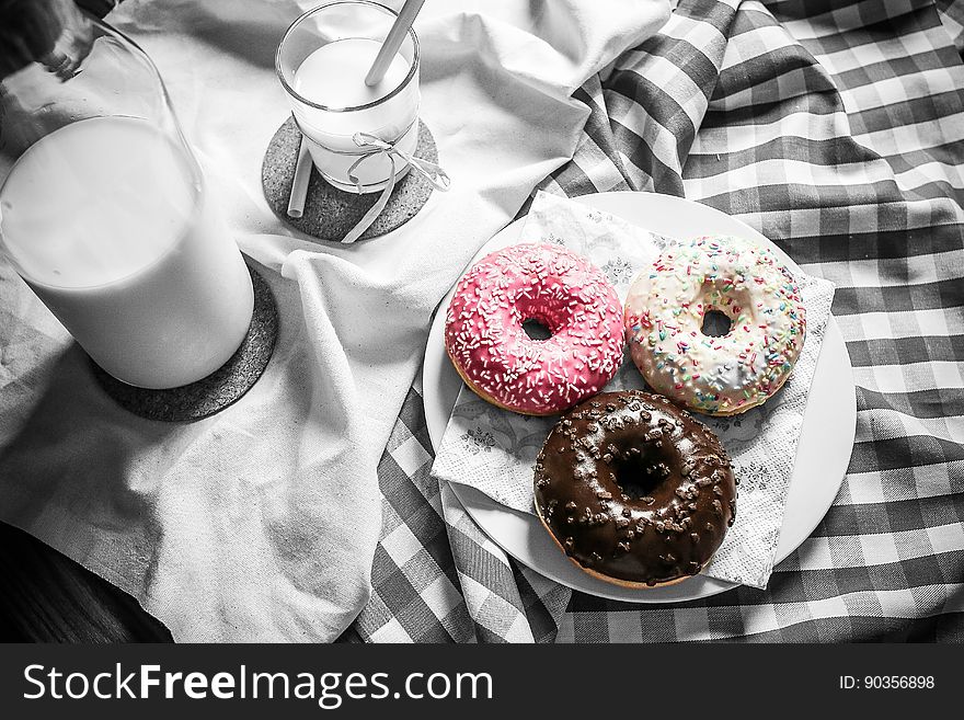 A jug of milk and a plate of donuts on table. A jug of milk and a plate of donuts on table.