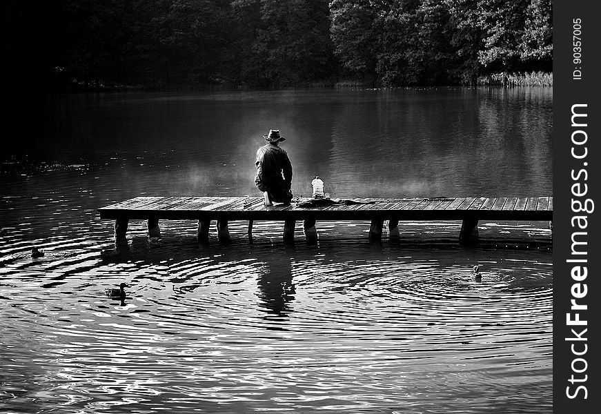 A black and white photo of a fisherman on a pier. A black and white photo of a fisherman on a pier.