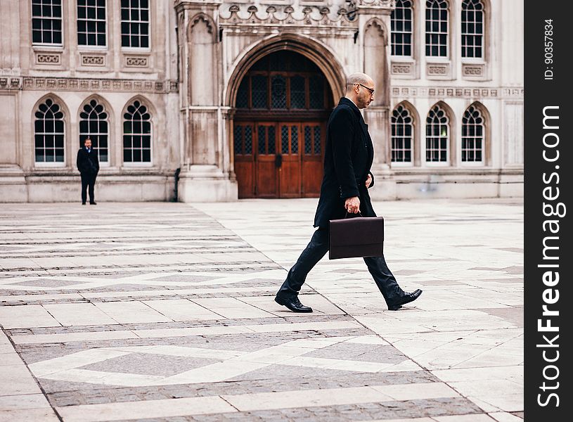 A businessman with a briefcase walking past a historic building. A businessman with a briefcase walking past a historic building.