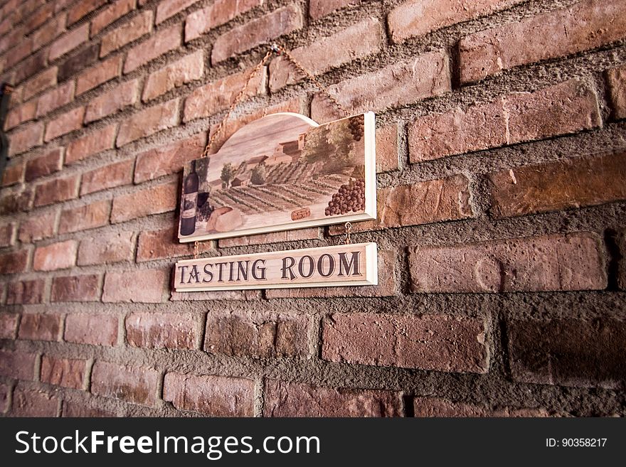 A brick wall with the sign for a tasting room.