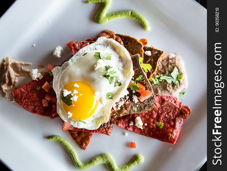 A plate with crisps and sauce with an egg on the top. A plate with crisps and sauce with an egg on the top.