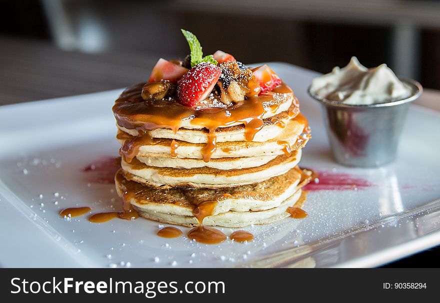 A stack of pancakes with caramel sauce and fresh fruits.