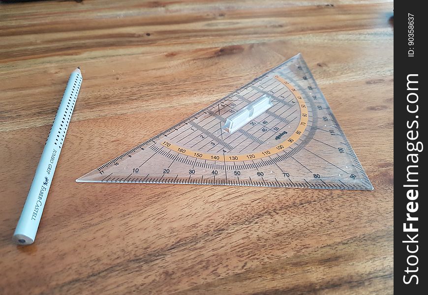 Geometric compass with triangular protractor on wooden desk.