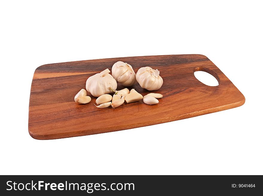 Three whole garlics and multiple cloves of garlic on brown cutting board. Isolated on white. Three whole garlics and multiple cloves of garlic on brown cutting board. Isolated on white.