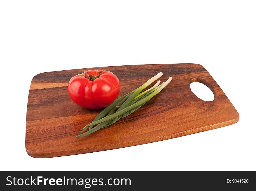 One red tomato and spring onions on brown cutting board. Isolated on white. One red tomato and spring onions on brown cutting board. Isolated on white.