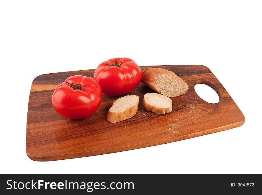 Two tomatoes and slices of baguette on cutting board. Isolated on white.