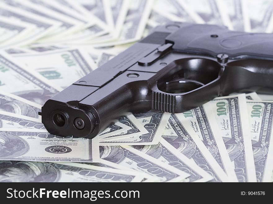 Black automatic pistol on background with one hundred dollar notes. Black automatic pistol on background with one hundred dollar notes