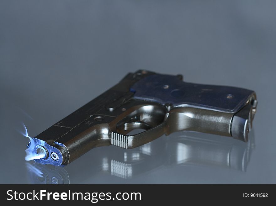 Black automatic pistol with smoke near barrel's hole lying on dark background. Black automatic pistol with smoke near barrel's hole lying on dark background