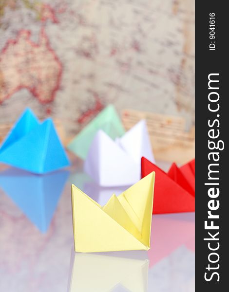 Colourful paper boats on background with old map