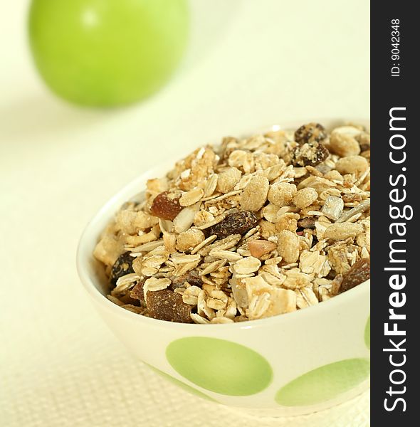 Muesli and green apple on beige background