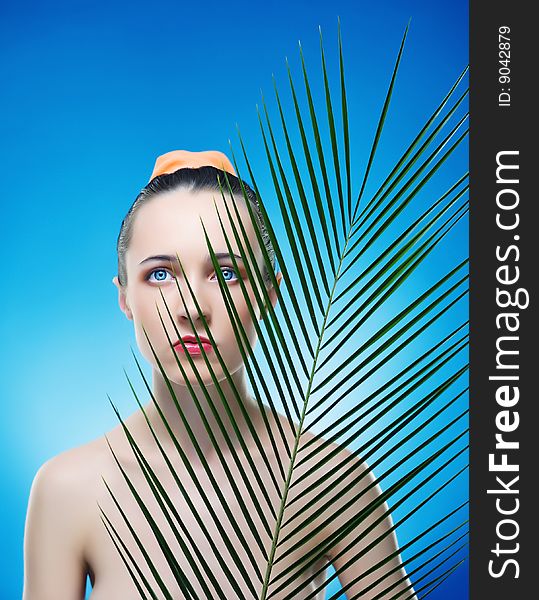 Portrait of beautiful woman with the plant by the sheet of palm. Expressive view of beautiful eyes. Portrait of beautiful woman with the plant by the sheet of palm. Expressive view of beautiful eyes.