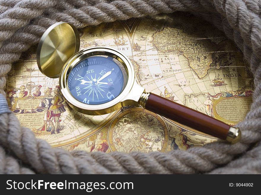 A beautiful golden compass and old rope. A beautiful golden compass and old rope
