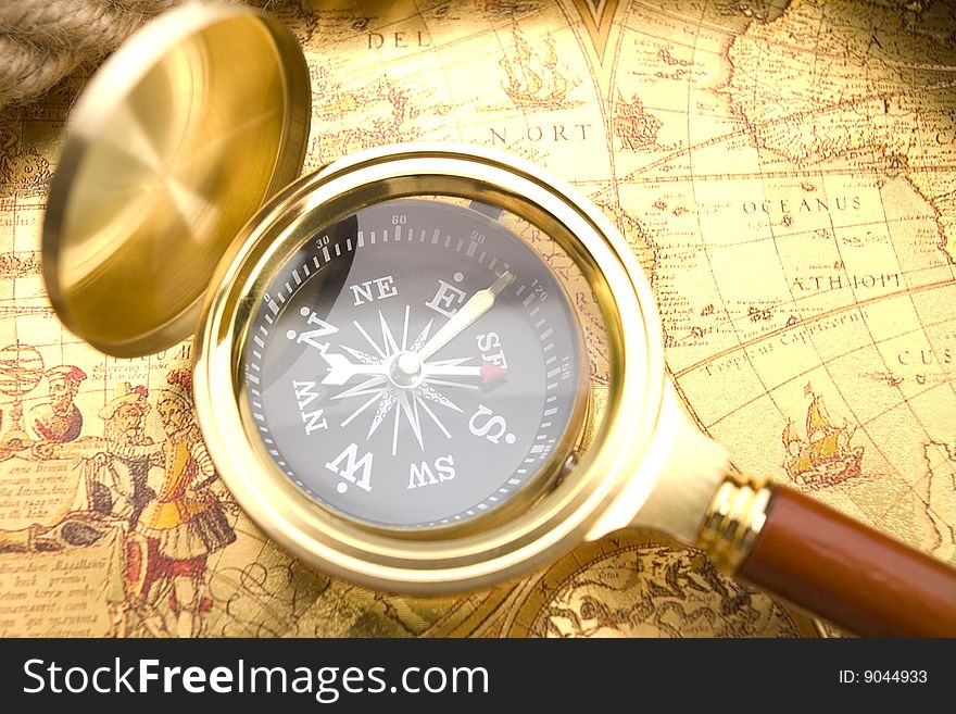 A beautiful golden compass and old magnifier. A beautiful golden compass and old magnifier