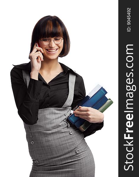 Smiled brunette schoolgirl talking by phone and hold books in the hands over white background