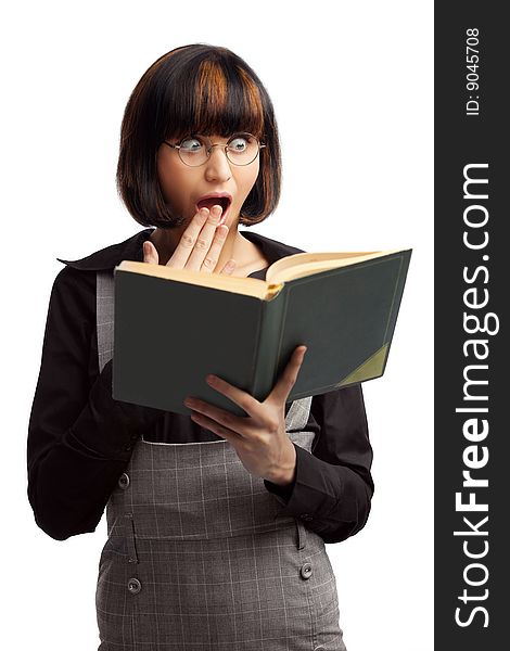 Surprised brunette schoolgirl looking in the book holding in her hands over white background