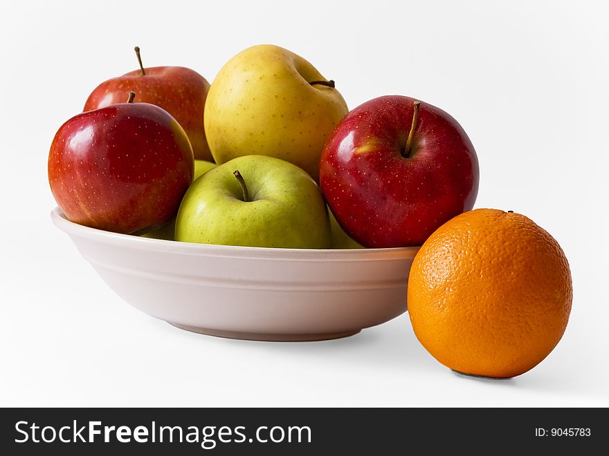 Apples on a plate and an orange against white background, isolated