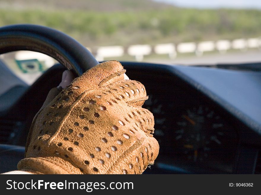 A man's hand with glove on the car's helm. A man's hand with glove on the car's helm