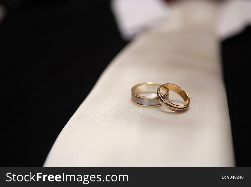Wedding rings resting on  grooms tie