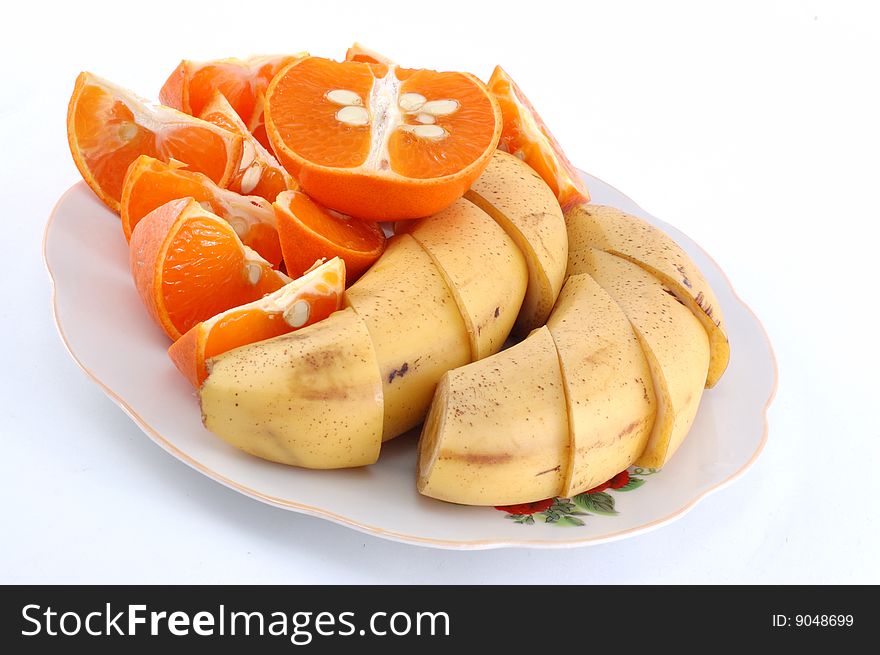 Cut bananas and mandarines on a white dish