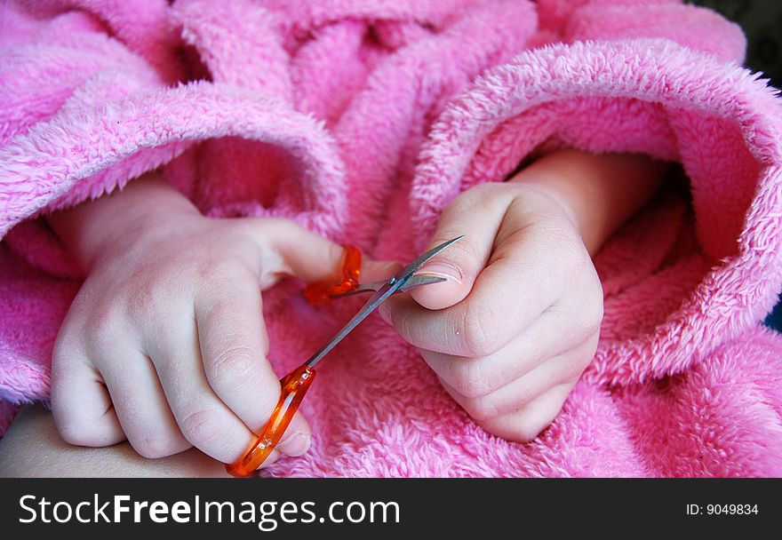 Girl in pink garment cutting her nails with cosmetic scissors. Girl in pink garment cutting her nails with cosmetic scissors