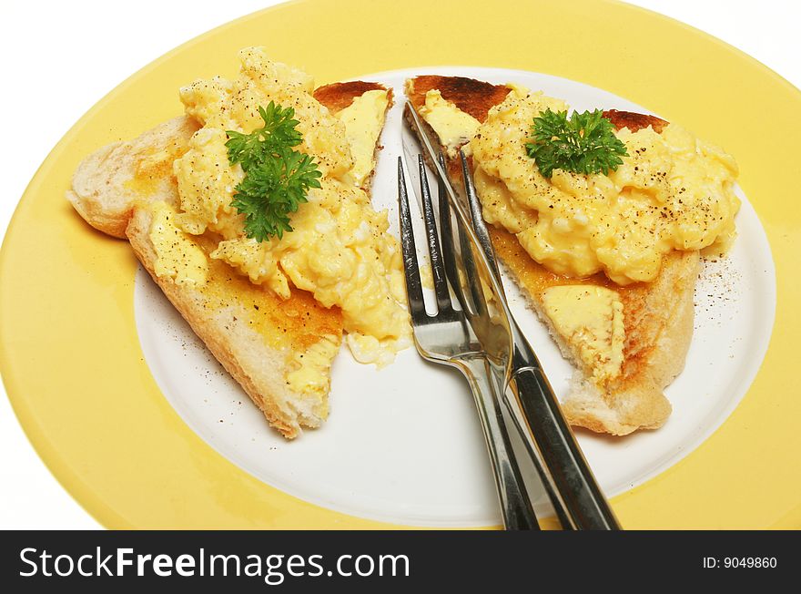 Scrambled eggs on toast with knife and fork on a plate