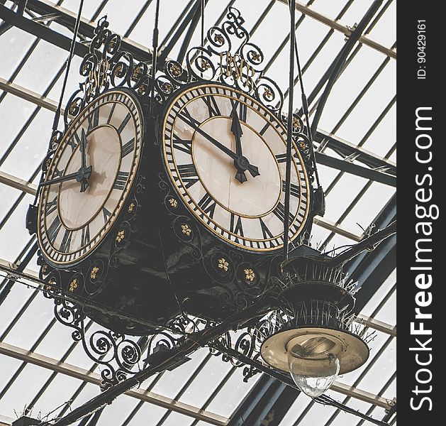 A vintage clock hanging from a glass ceiling.