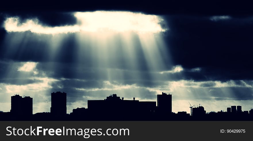 Crepuscular rays coming down from the clouds over a city.