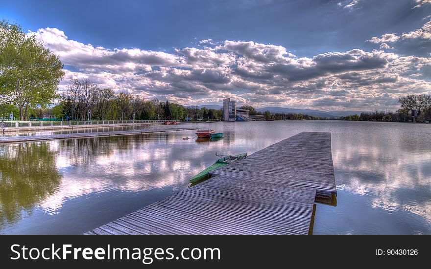 A wooden pier in the water with cloudy skies above. A wooden pier in the water with cloudy skies above.