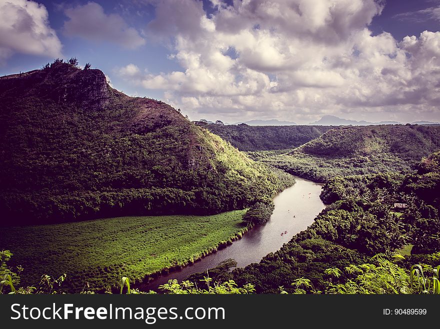 Elevated view of curving river in green valley next to mountain, cloudscape background. Elevated view of curving river in green valley next to mountain, cloudscape background.