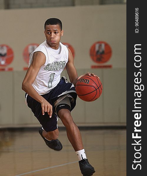 An African-American Basketball player dribbling the ball.