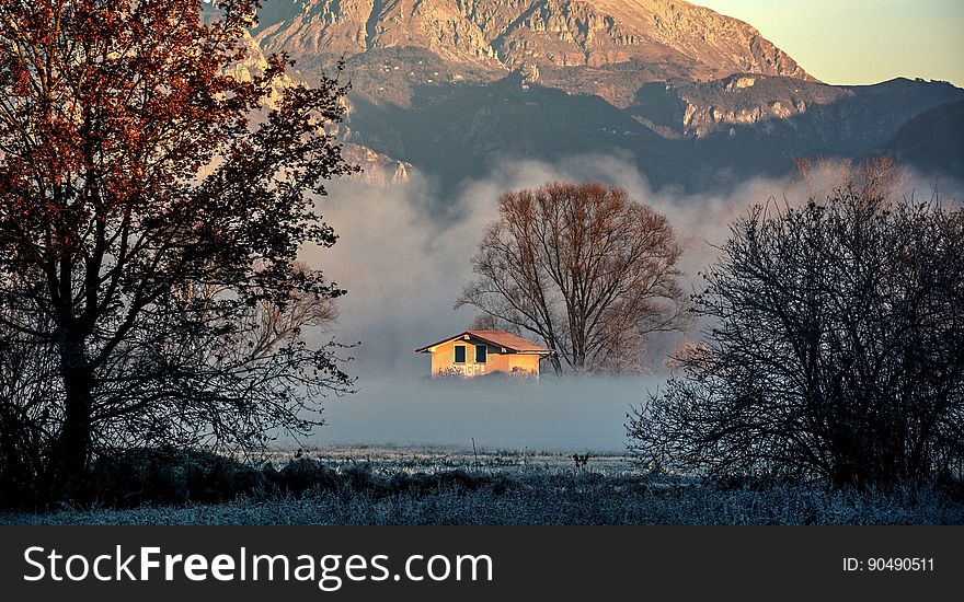 A cabin in the woods with mountains in the background and mist settling in to the land. A cabin in the woods with mountains in the background and mist settling in to the land.