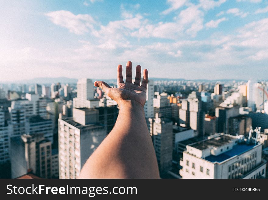 Distorted closeup of hand and arm with an urban cityscape background, in distance blue sky and thin cloud. Distorted closeup of hand and arm with an urban cityscape background, in distance blue sky and thin cloud.