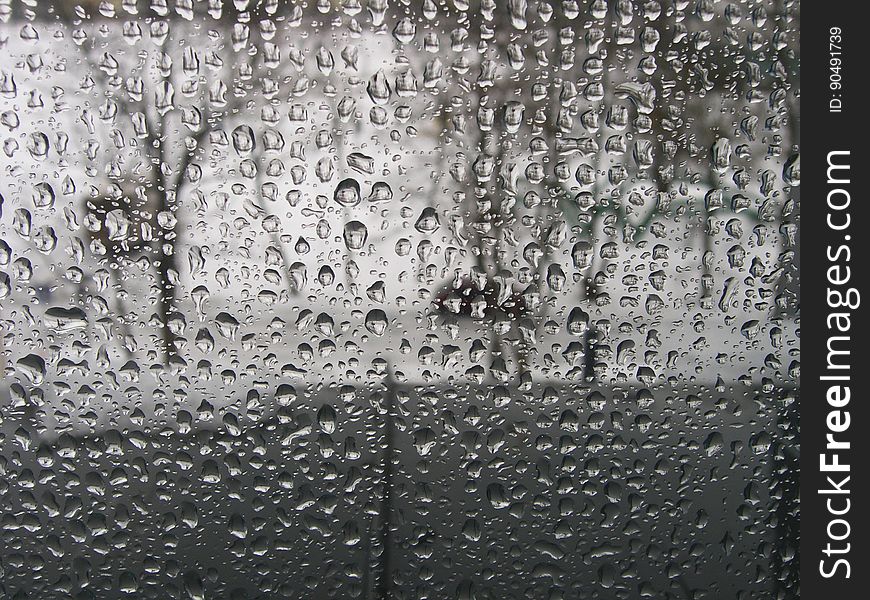 Raindrops on window pane allowing only blurred image of trees (in park) beyond.