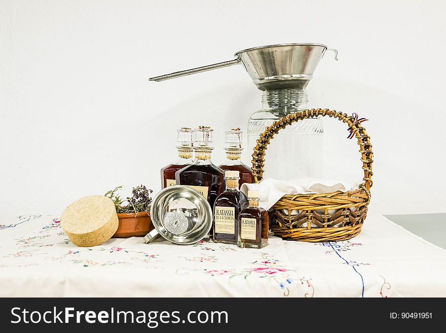 Brown Woven Basket Beside Clear Bottle on White Table Clothe