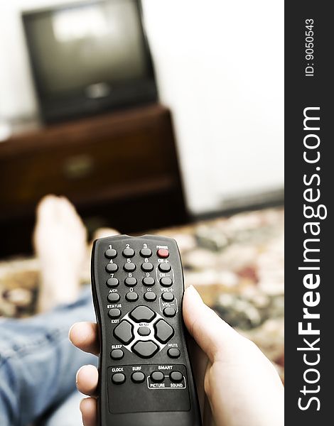 A hand holding a controller raised to change the station or turn the television on. A hand holding a controller raised to change the station or turn the television on.