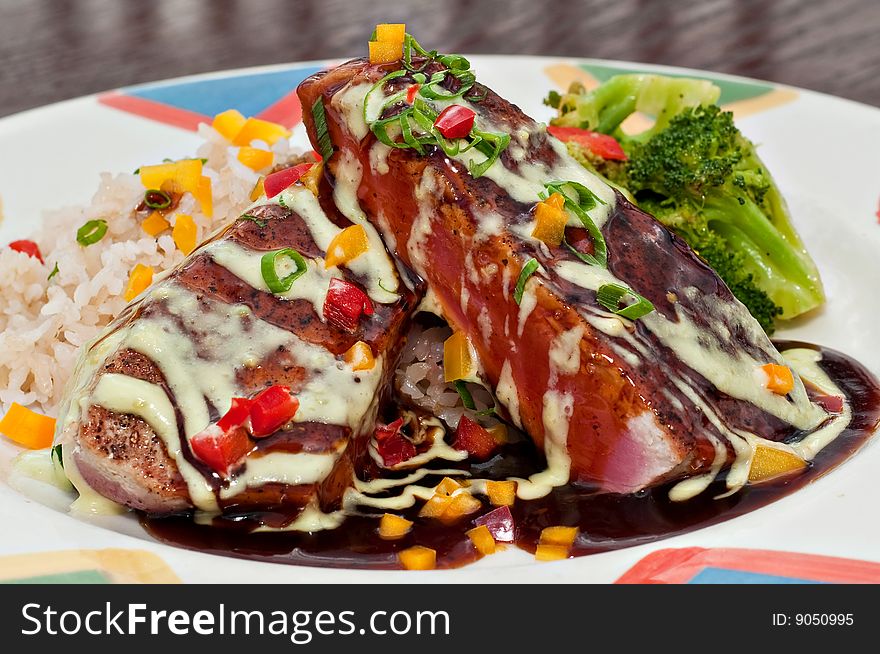 Dish with grilled tuna fillets over rice with vegetables and red wine reduction and Hollandaise sauce. Dish with grilled tuna fillets over rice with vegetables and red wine reduction and Hollandaise sauce