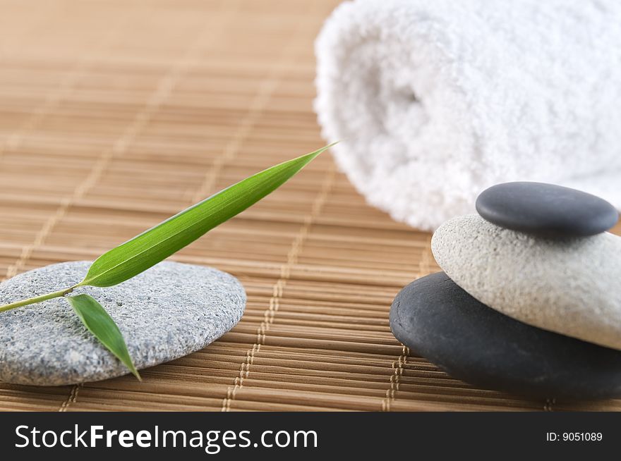 Bamboo leaf and stones on a bamboo mat with towel in the background. Bamboo leaf and stones on a bamboo mat with towel in the background