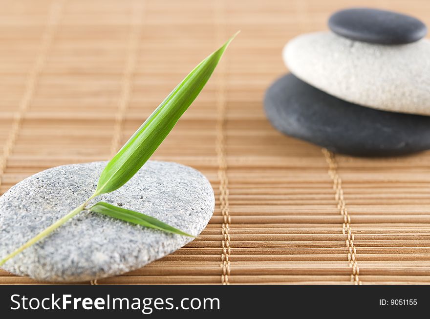 Bamboo leaf and a stack of stones on a bamboo mat. Bamboo leaf and a stack of stones on a bamboo mat