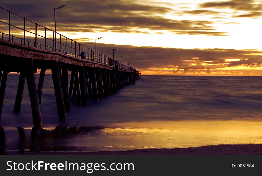 A jetty at sunset with beach, ocean and sky. Men fishing from jetty also. A jetty at sunset with beach, ocean and sky. Men fishing from jetty also.