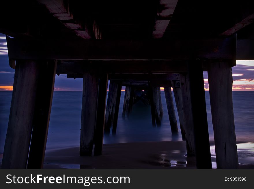 A jetty at sunset with beach, ocean and sky. Men fishing from jetty also. A jetty at sunset with beach, ocean and sky. Men fishing from jetty also.