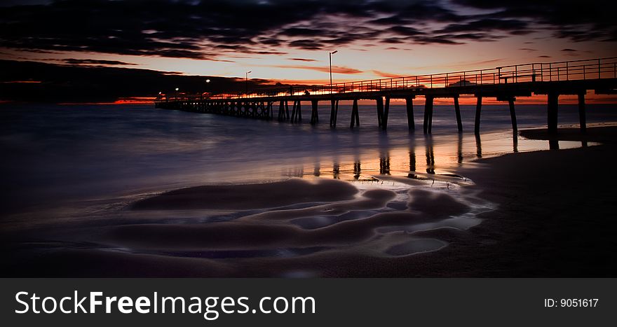 A jetty at sunset with beach, ocean and sky. Men fishing from jetty also. A jetty at sunset with beach, ocean and sky. Men fishing from jetty also.