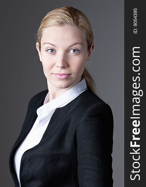 A portrait of a blue eyed blonde haired businesswoman on a gray background