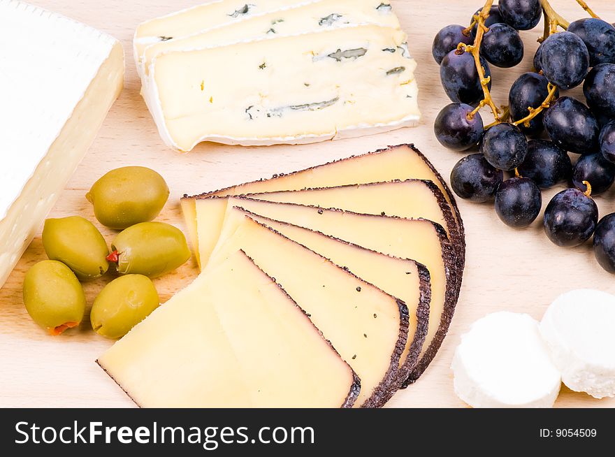 Cheese with olives and grapes on the hardboard. Cheese with olives and grapes on the hardboard