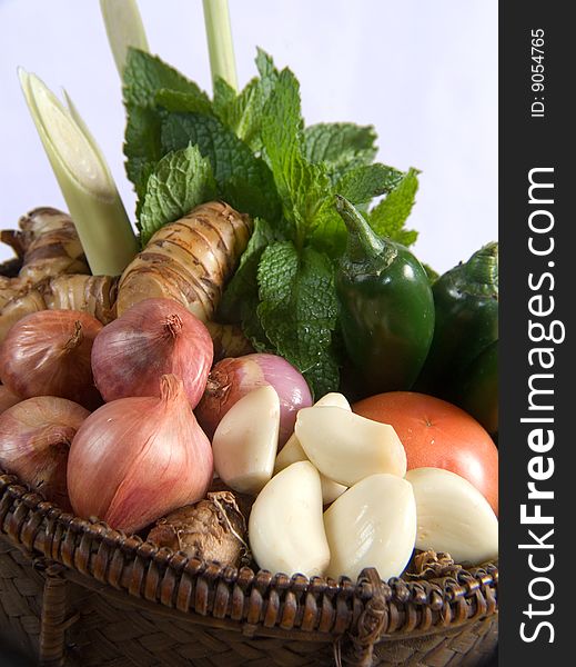 Fresh basket of herbs and vegetables with a white background