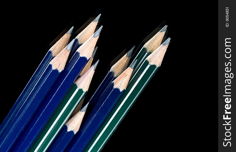 Kit of green and blue pencils on black background