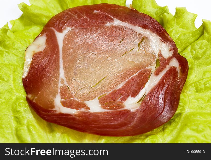 Slice of the smoked meat on the green sheet of lettuce