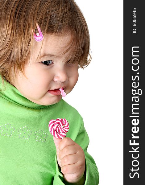 Toddler girl with chubby cheeks eating a sticky lollipop