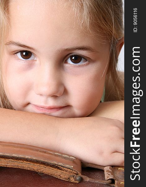 Beautiful young girl resting on an antique suitcase. Beautiful young girl resting on an antique suitcase